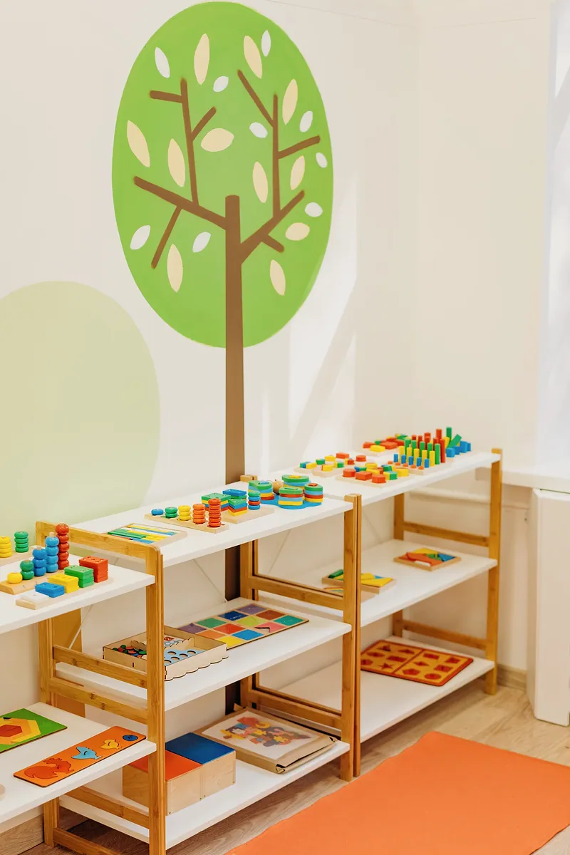 Estantes con juguetes didácticos de madera en una sala infantil luminosa.